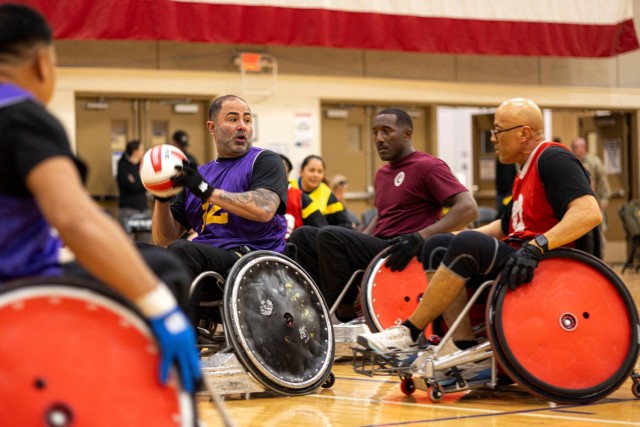 U.S. Army Capt. Carlos Rivera, left, prepares to throw the ball before being defended by Master Sgt. Earlie Brown, center, and Sgt. 1st Class David Hoang, right, during wheelchair rugby practice at the 2025 Army Trials, Fort Bliss, Texas, April 4, 2025.